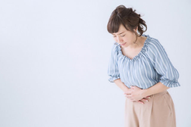 お腹を抱える女性の写真